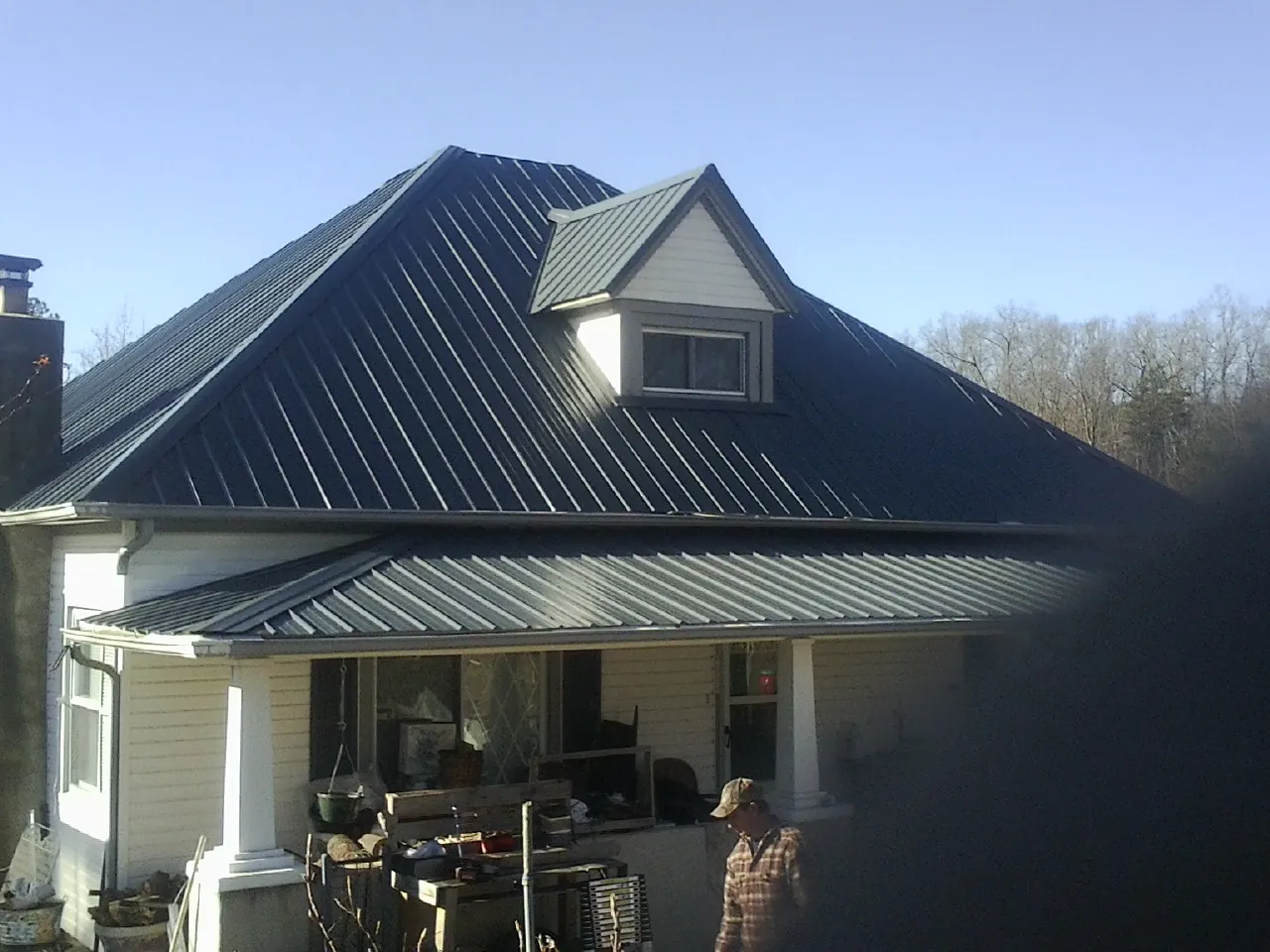 Dark blue standing seam metal roof with a dormer above a front porch in Ashford