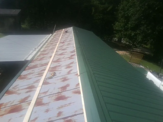 Old rusted panels beside newly installed green metal roofing — Wind Damage Roof Repair by Roofing Brothers in Ashford