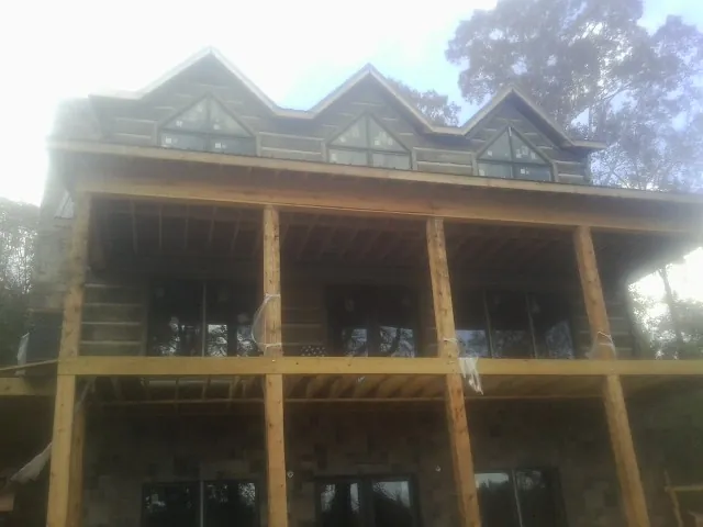 Dormers and porch framing on a large log home under construction — Roof Coating work by our crew in Ashford